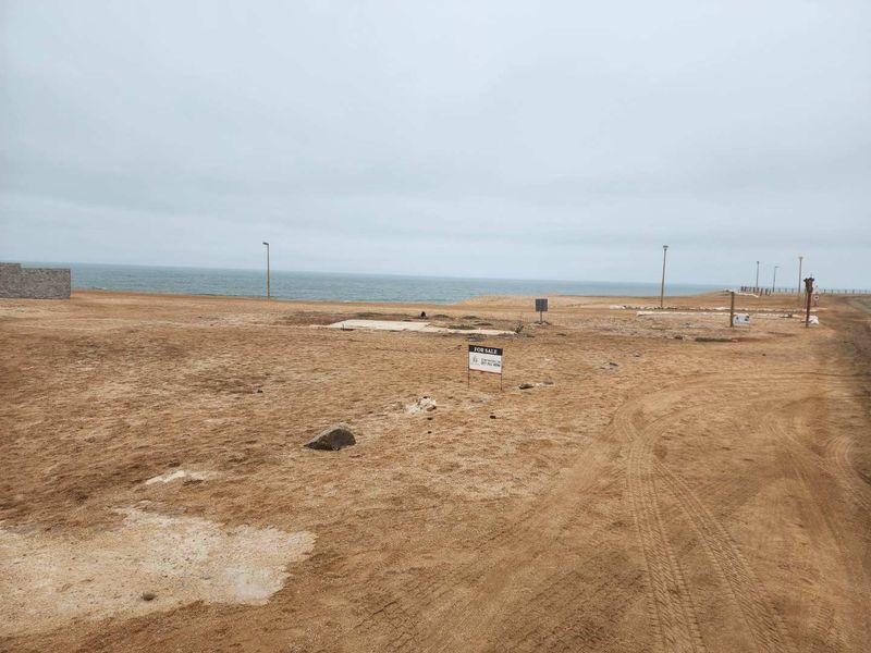 Vacant residential land plot featuring ocean views, a concrete slab foundation, and established street lighting in a coastal development.