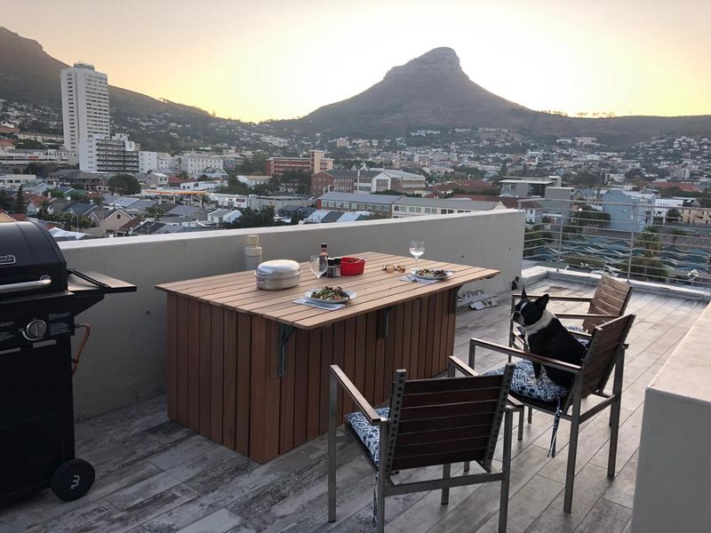 Spacious rooftop balcony featuring tiled flooring, a parapet wall, and metal railings, offering panoramic mountain and city views.