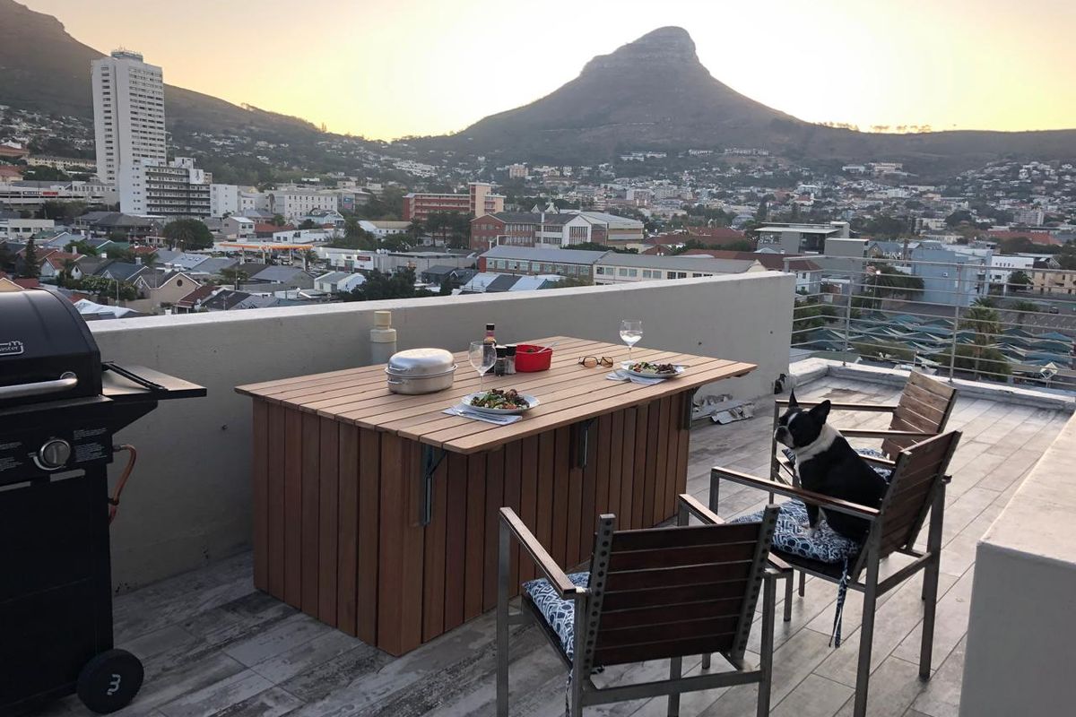 Spacious rooftop balcony featuring tiled flooring, a parapet wall, and metal railings, offering panoramic mountain and city views.