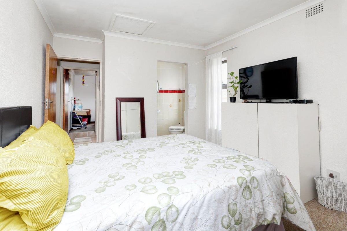 A bedroom featuring an en-suite bathroom, neutral wall finishes, and coving, providing a functional living space with potential for cosmetic updates.