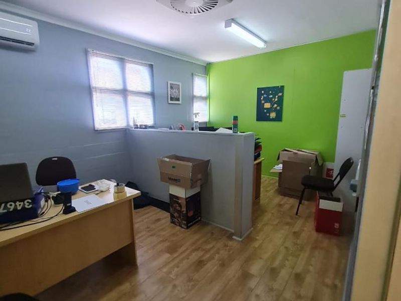 A functional office space featuring laminate flooring, partition walls, and integrated air conditioning units, providing a practical layout for a professional work environment.