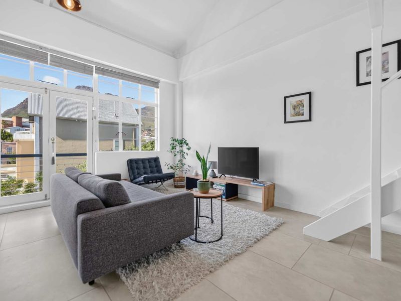 Bright and airy living room featuring high ceilings, large windows, and direct access to a balcony with mountain views.
