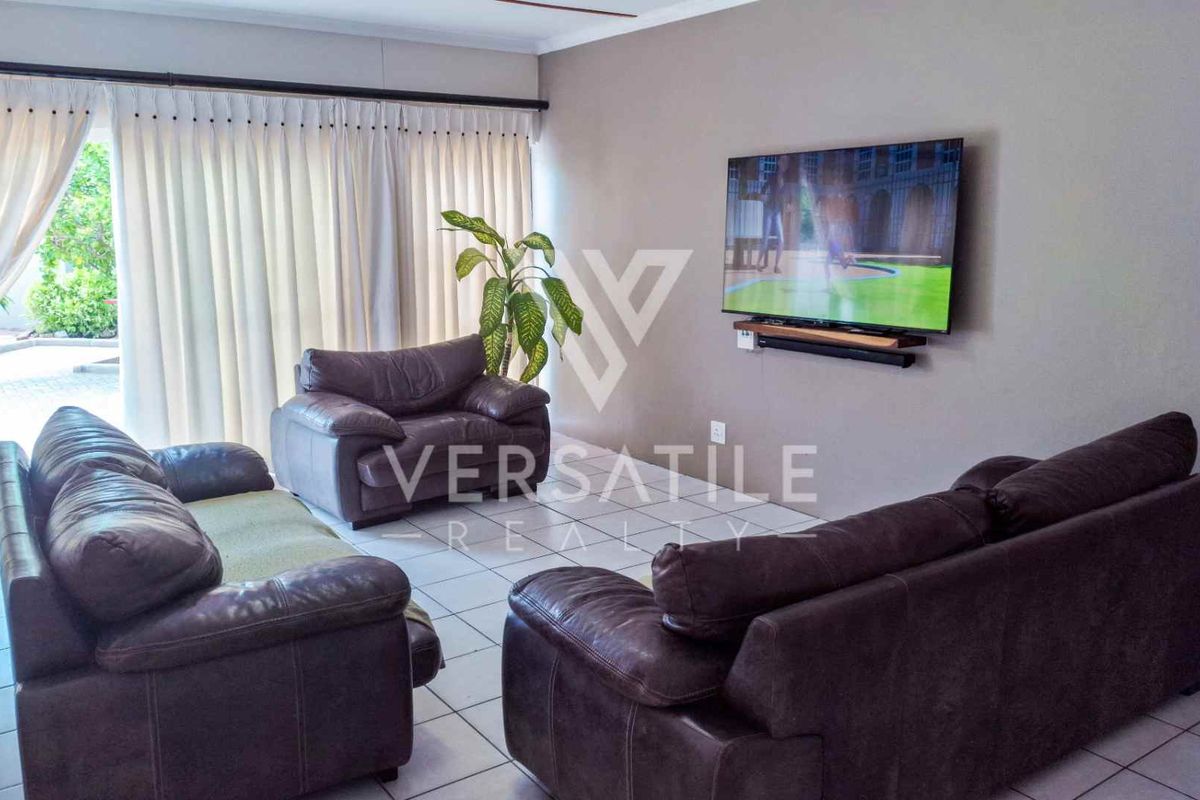 A comfortable living room featuring tiled flooring and large sliding glass doors that provide access to the outdoor area.