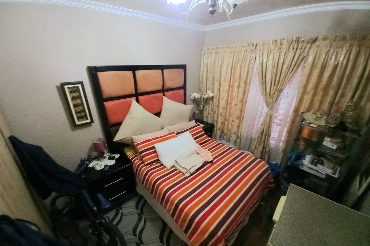 A bedroom featuring a built-in headboard, crown molding, and floor-to-ceiling curtains.