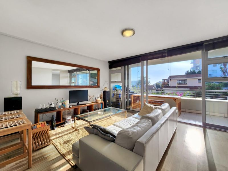 Bright living room featuring laminate flooring and large sliding glass doors providing direct access to a private balcony.