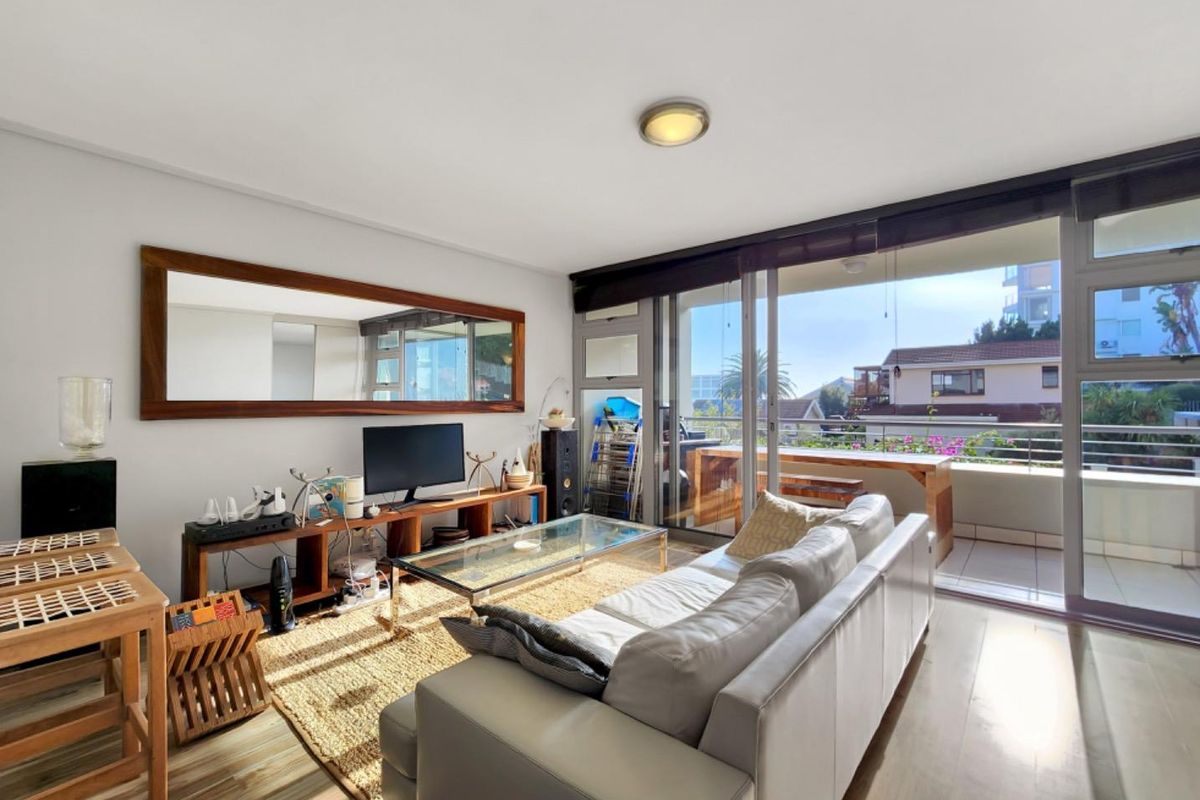 Bright living room featuring laminate flooring and large sliding glass doors providing direct access to a private balcony.