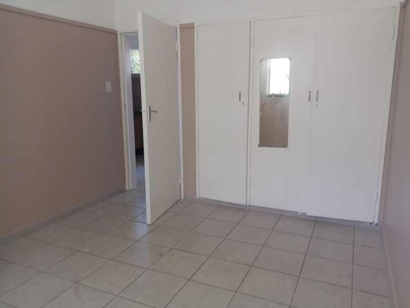 An empty bedroom featuring tiled flooring and built-in cupboards, offering a blank canvas for personalization.