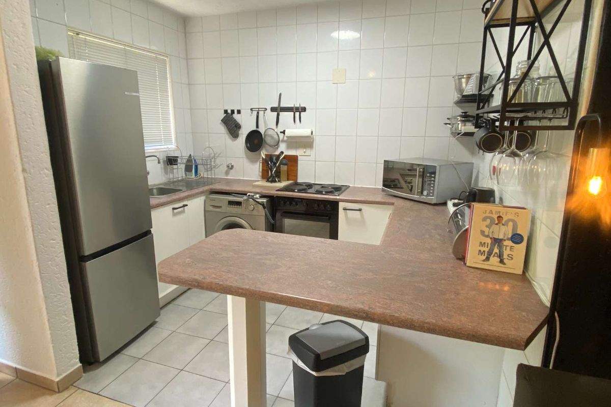 Functional kitchen featuring laminate countertops, tiled backsplash, built-in oven, hob, and integrated laundry plumbing, offering a practical layout for daily meal preparation.