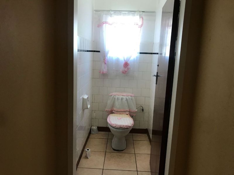 A compact bathroom featuring ceramic wall and floor tiles with a standard toilet fixture.