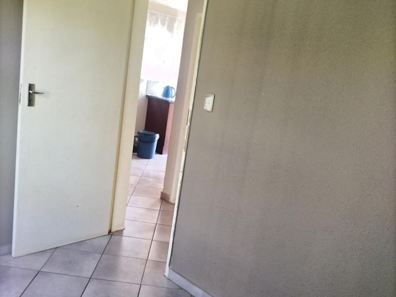 A vacant hallway featuring tiled flooring and neutral wall finishes, providing access to adjacent rooms within the property.