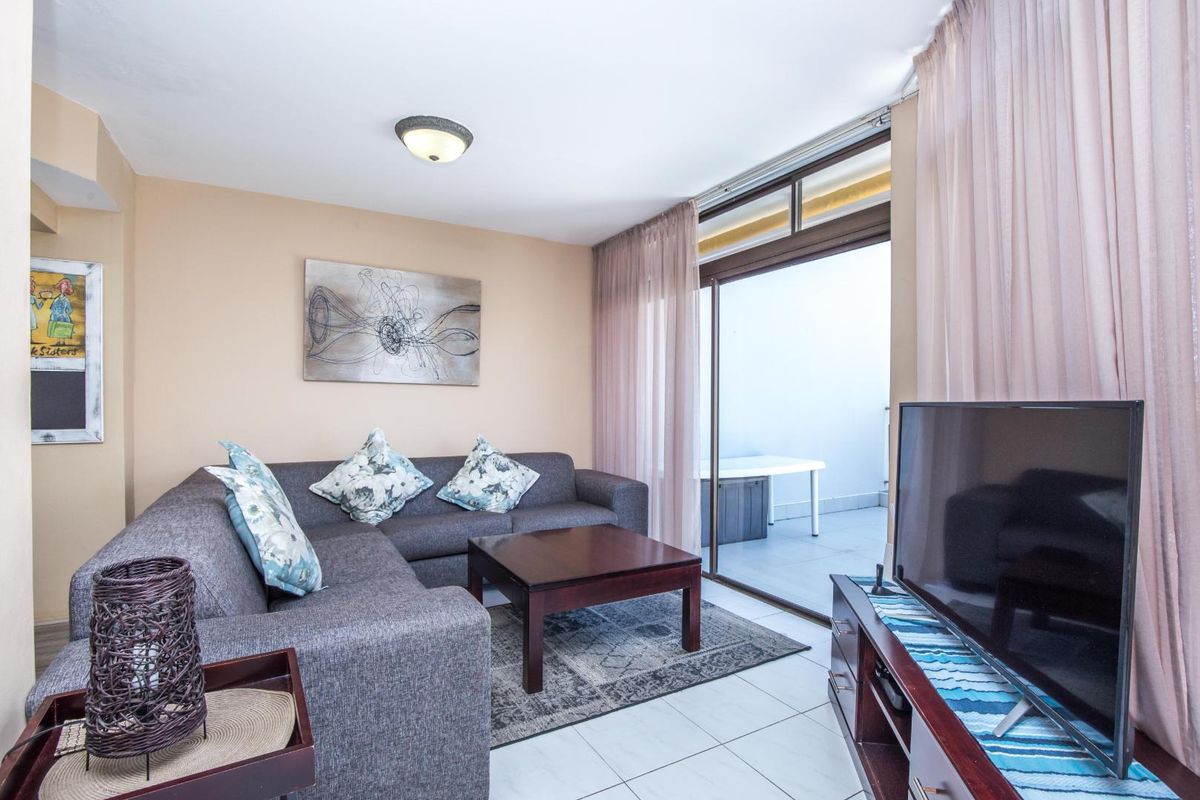 A comfortable living room featuring tiled flooring and large sliding glass doors that provide direct access to an outdoor balcony area.