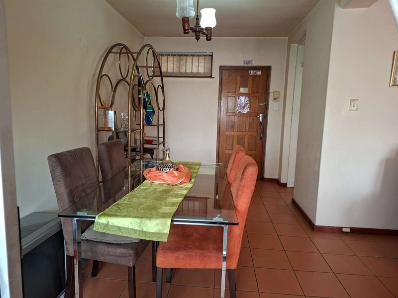 A dining area featuring tiled flooring and a timber entrance door, offering a functional space for meals.