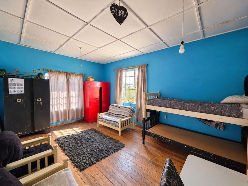 A bedroom featuring original timber flooring, a tiled ceiling, and a casement window, currently requiring cosmetic updates and refurbishment.