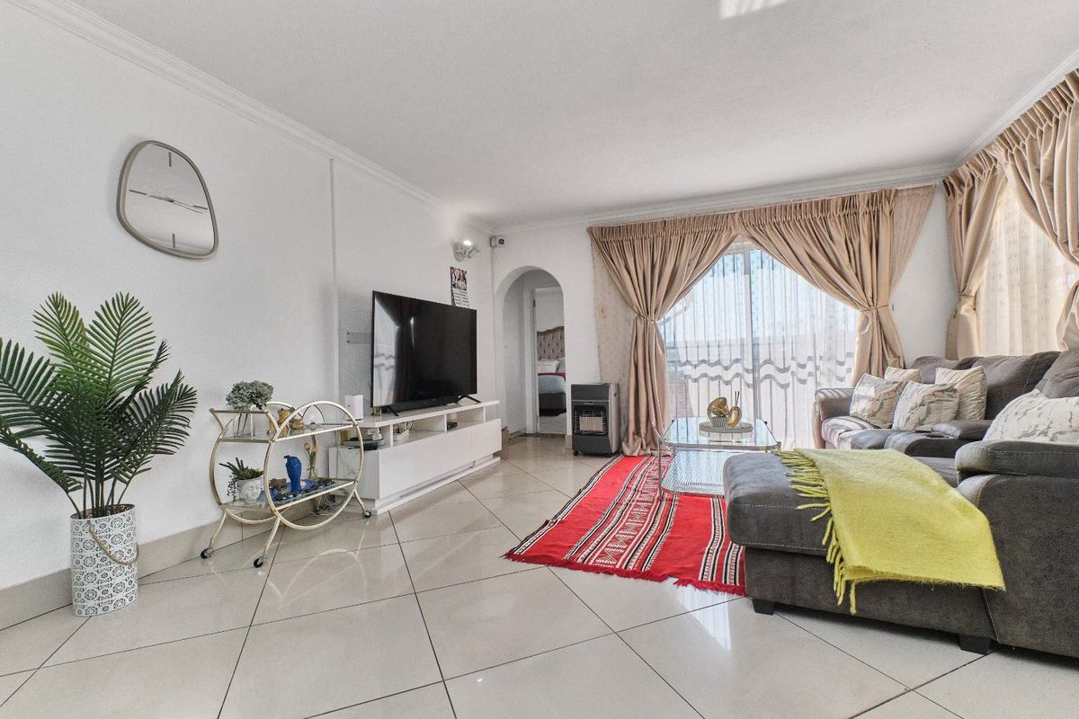 A bright living room featuring polished tiled flooring, an arched entryway, and a large sliding glass door providing access to the exterior.