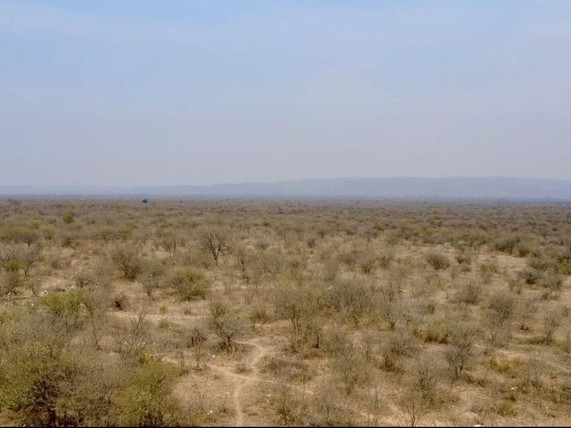 Expansive aerial view of the surrounding rural landscape and natural vegetation characteristic of the farm property.