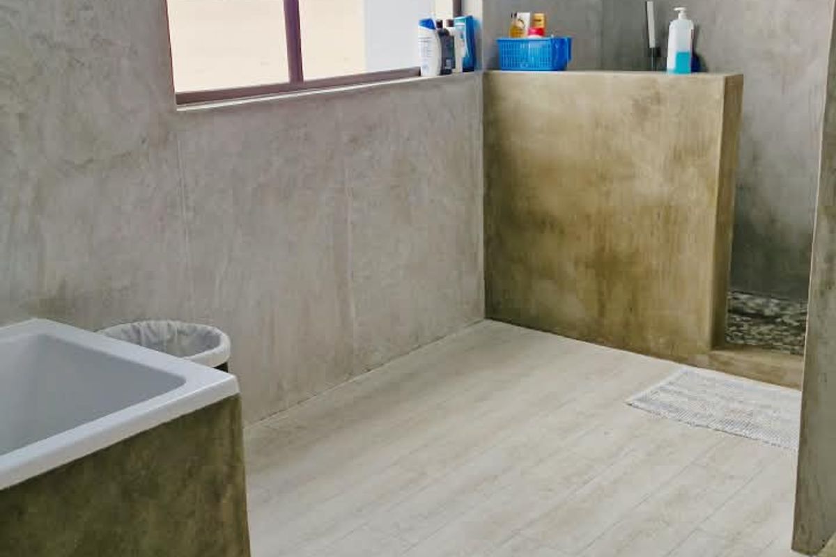 Modern bathroom featuring a walk-in shower, built-in bathtub, and industrial-style cement wall finishes with wood-look tile flooring.