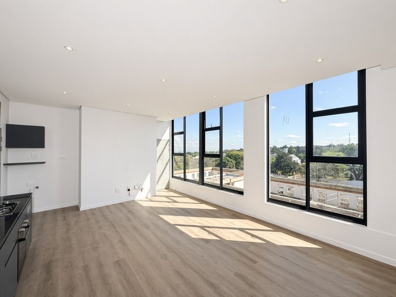 Bright and modern open-plan living area featuring laminate flooring, recessed lighting, and large windows offering expansive views.