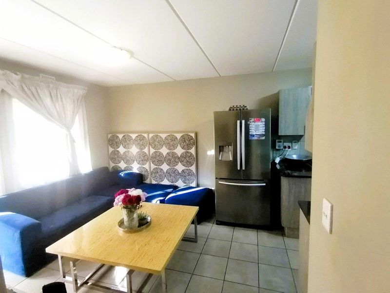 Open plan living area featuring tiled flooring and a compact kitchen with built-in cabinetry and stone countertops.