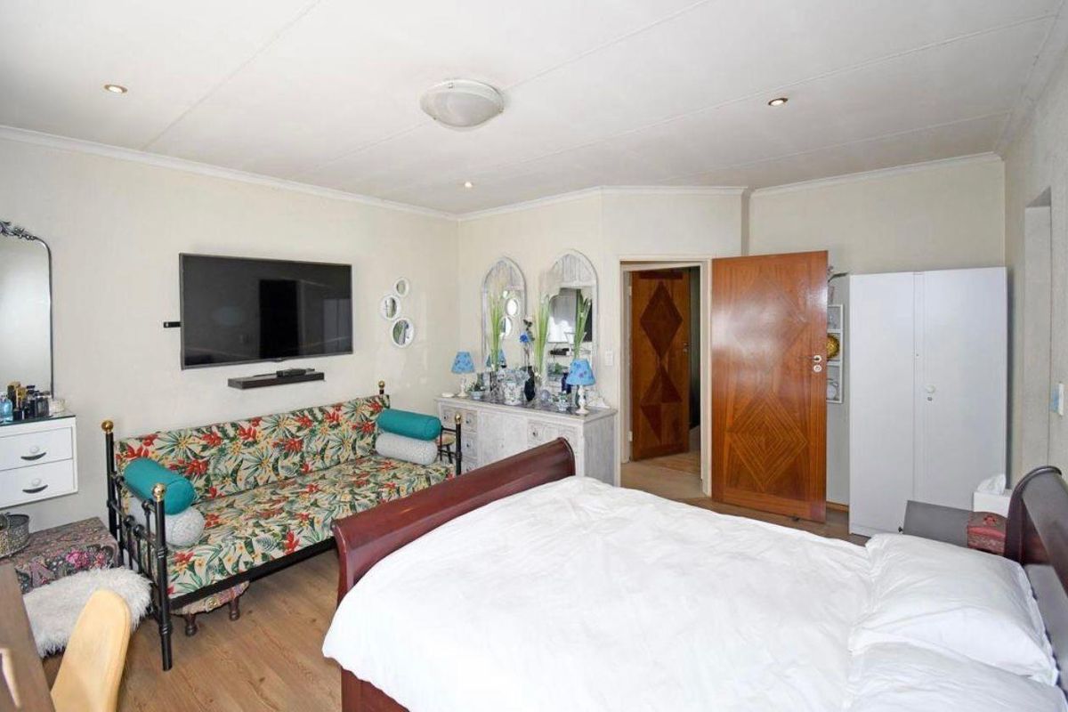 A spacious bedroom featuring laminate flooring, neutral walls, and a solid wood door, offering a functional layout with ample space for furniture.