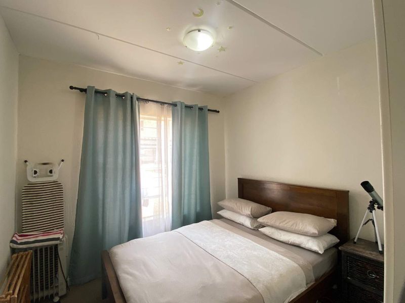 A functional bedroom featuring a window with curtains and a central ceiling light fixture.