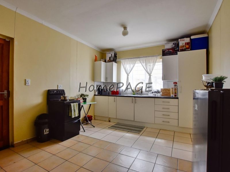 A functional kitchen featuring tiled flooring, built-in cabinetry, and a freestanding stove, offering a practical layout with potential for cosmetic updates.