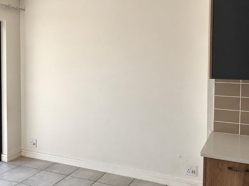 A clean, empty kitchen area featuring neutral tiled flooring, modern cabinetry, and a tiled backsplash, ready for personalization.