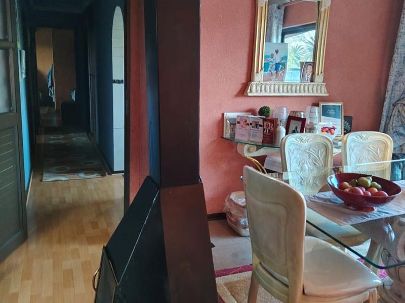 Dining area featuring a prominent freestanding fireplace, laminate flooring, and decorative ceiling cornicing, leading into a hallway.