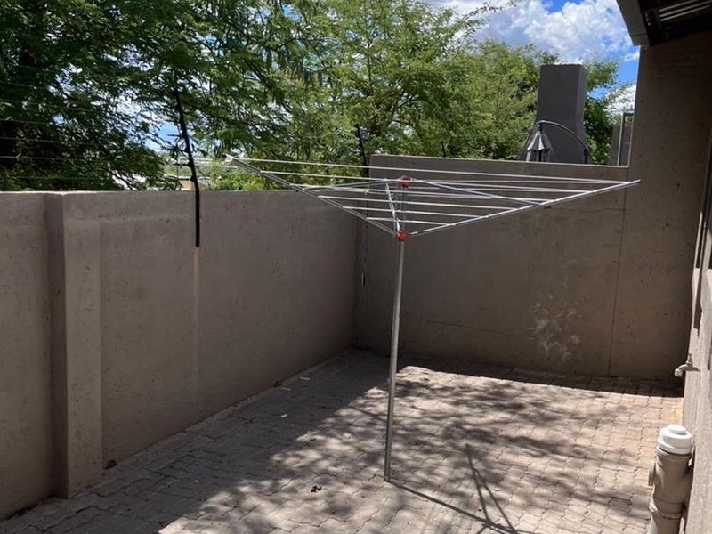 A paved outdoor patio area featuring perimeter walls with electric fencing and external plumbing fixtures.
