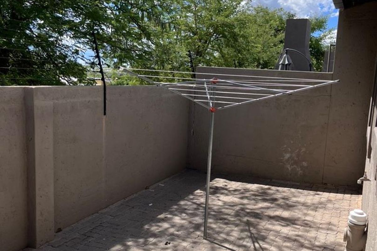 A paved outdoor patio area featuring perimeter walls with electric fencing and external plumbing fixtures.