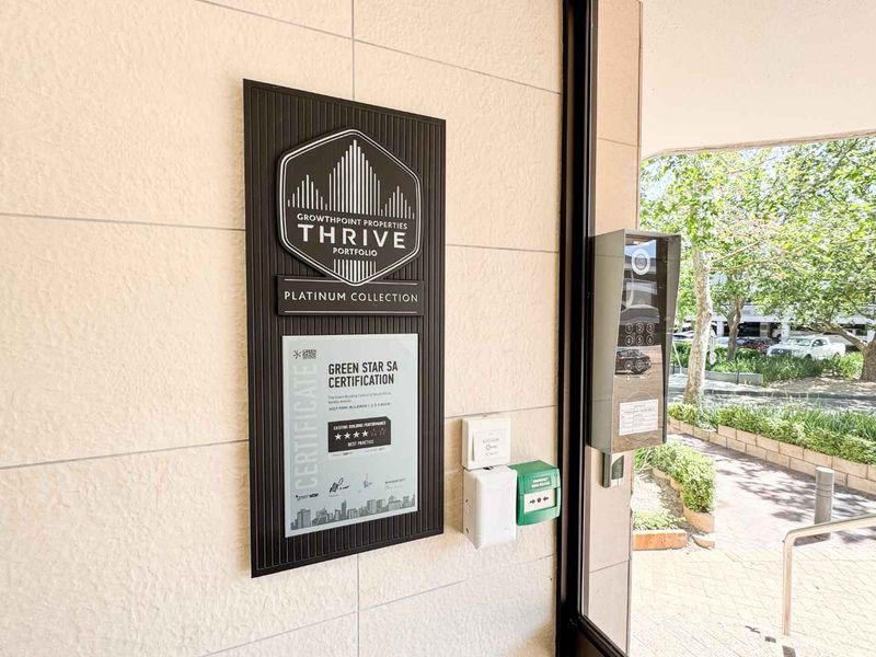Entrance area featuring building certification signage, intercom system, and access control infrastructure.