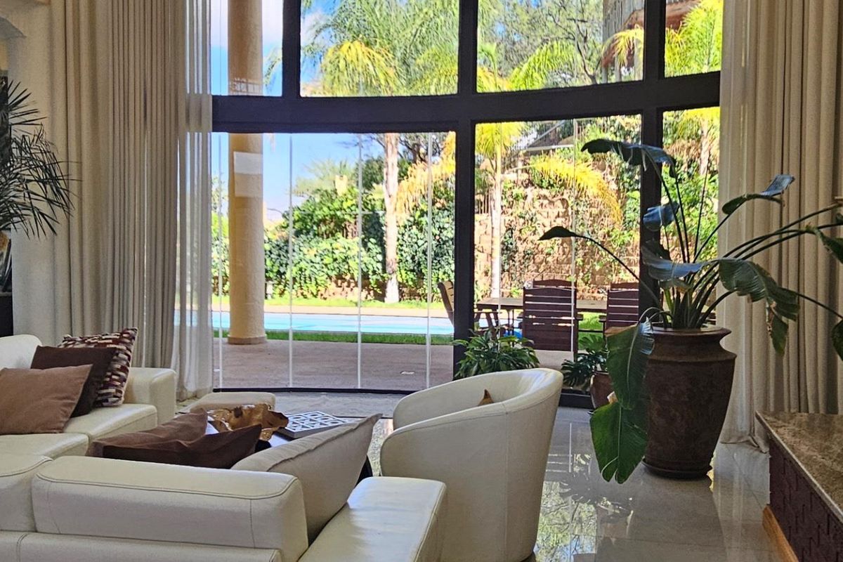 Spacious living area featuring floor-to-ceiling windows, a modern built-in fireplace, and seamless access to the outdoor patio and pool area.