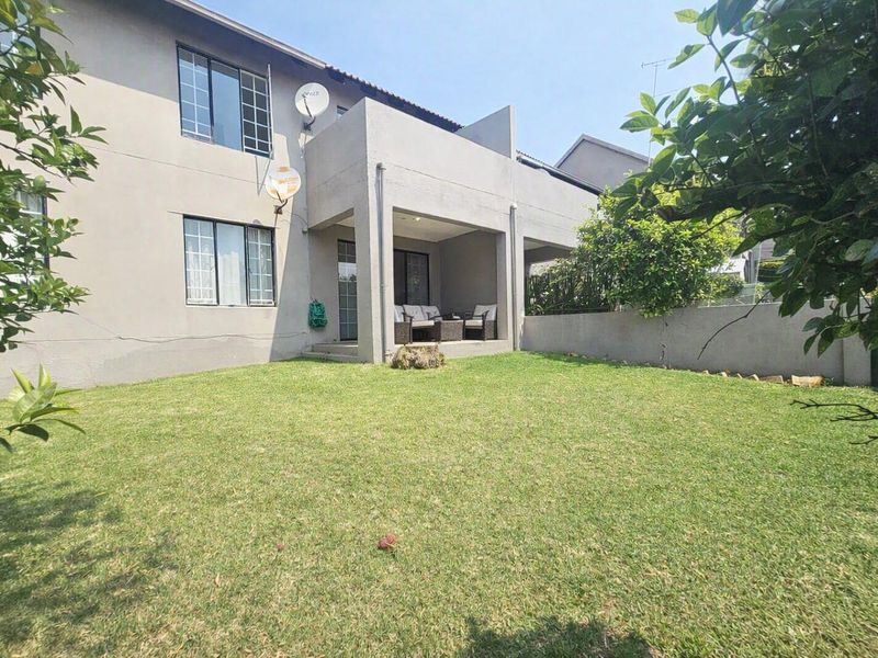 Rear view of the apartment featuring a private garden, a covered patio area, and exterior wall finishes.