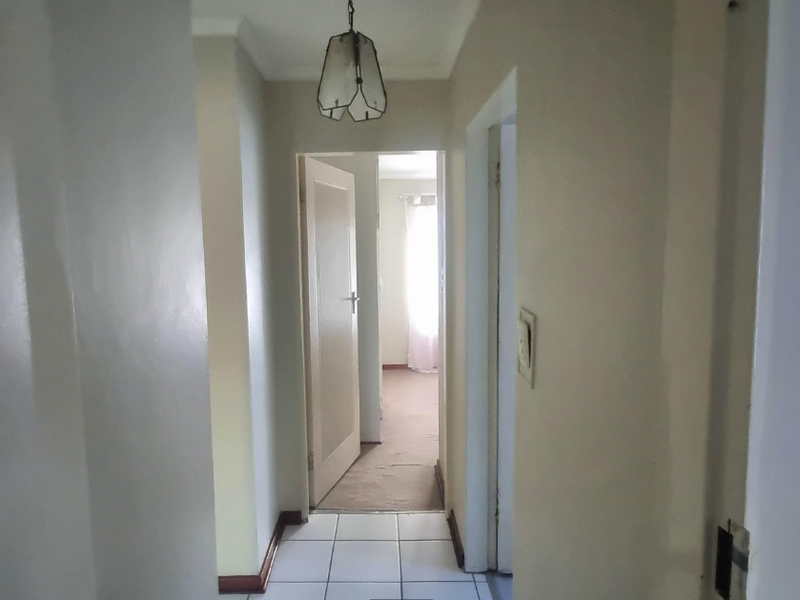 A functional hallway featuring tiled flooring, coved ceilings, and access to multiple rooms, providing a neutral foundation for interior updates.