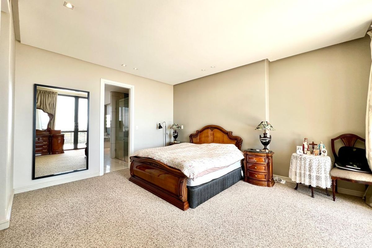 Spacious bedroom featuring neutral wall finishes, recessed downlighting, fitted carpeting, and direct access to an en-suite bathroom.