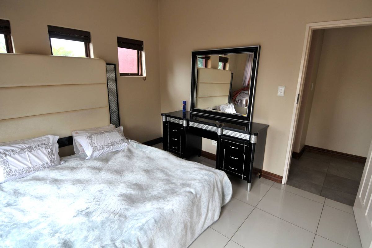 A bedroom featuring tiled flooring, neutral wall tones, and multiple windows, providing a functional and well-lit sleeping space.