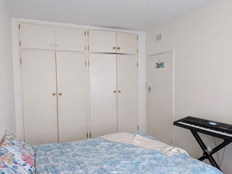 A bedroom featuring floor-to-ceiling built-in cupboards with integrated overhead storage units, providing ample storage space.