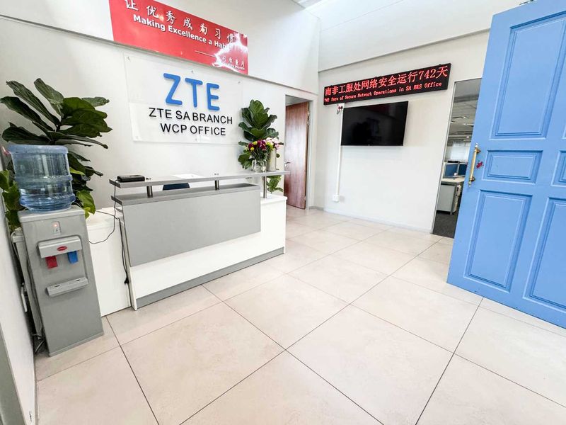 Professional office reception area featuring tiled flooring, a built-in reception desk, and a bright, welcoming entrance with a blue panelled door.