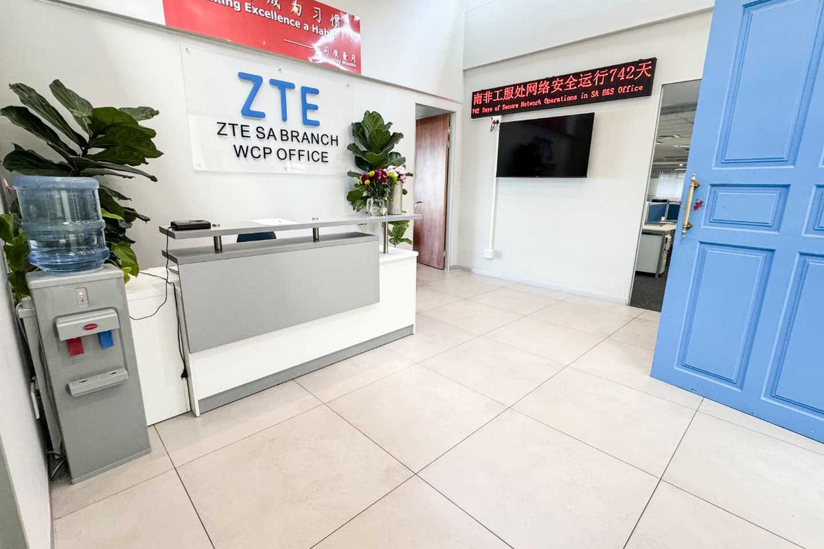 Professional office reception area featuring tiled flooring, a built-in reception desk, and a bright, welcoming entrance with a blue panelled door.