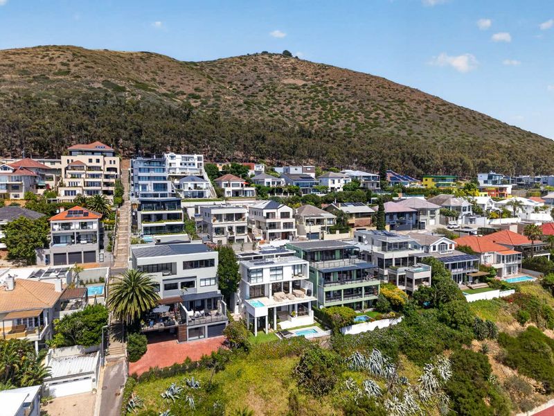 An aerial view of a coastal residential neighborhood situated on a hillside, showcasing the density and layout of the surrounding apartment and house properties.