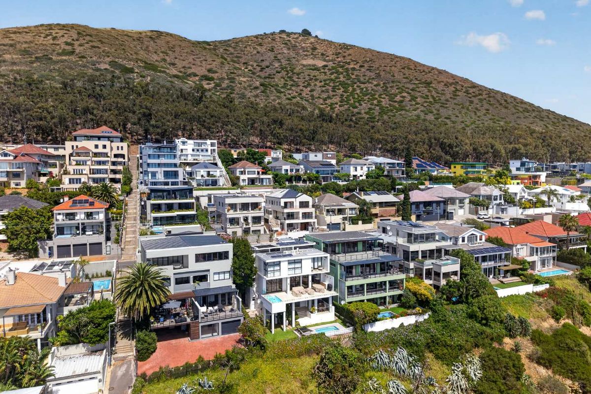 An aerial view of a coastal residential neighborhood situated on a hillside, showcasing the density and layout of the surrounding apartment and house properties.