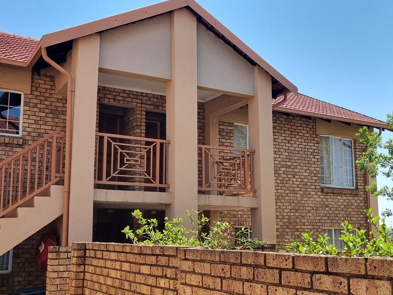 Exterior view of a face brick apartment building featuring a tiled roof, external staircase, and metal balustrades.