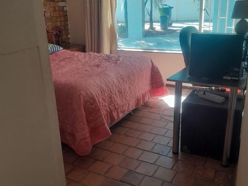 Bedroom featuring exposed brick wall detail, terracotta tile flooring, and large sliding glass door providing access to the outdoor patio area.