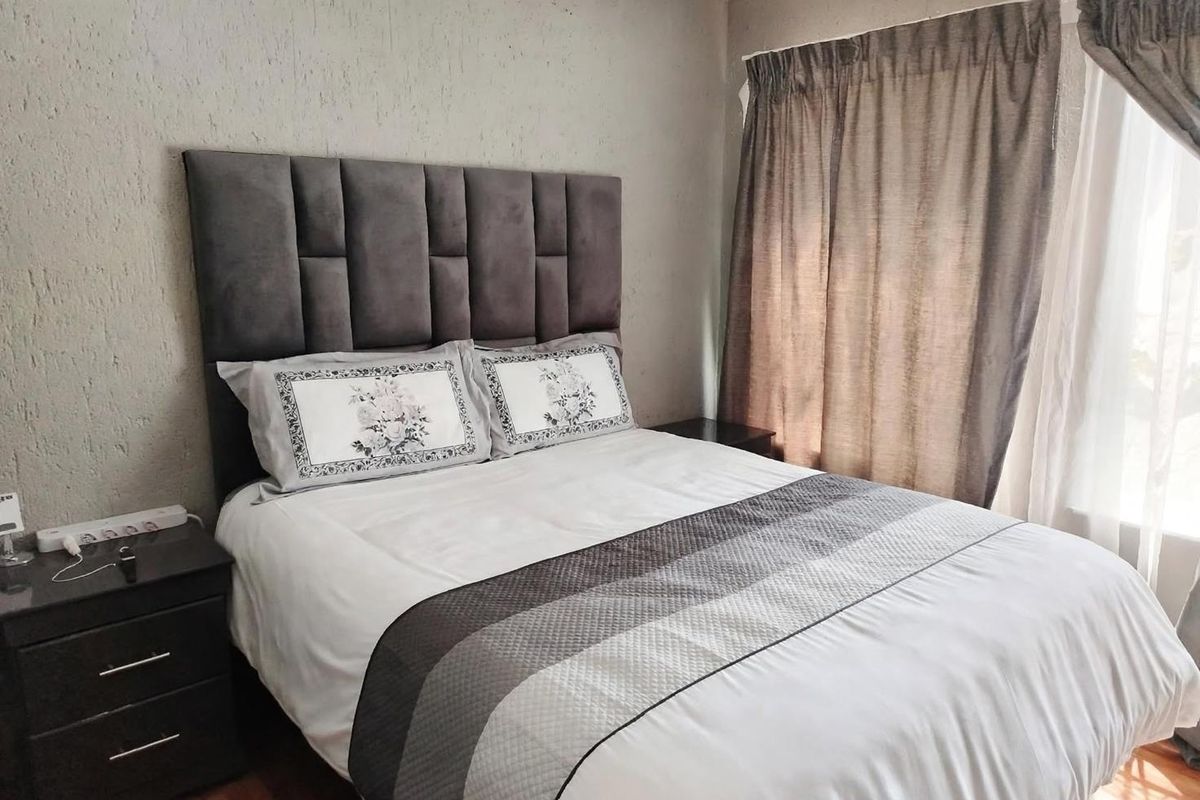 A cozy bedroom featuring textured wall finishes and window curtain treatments, providing a neutral foundation for personal styling.