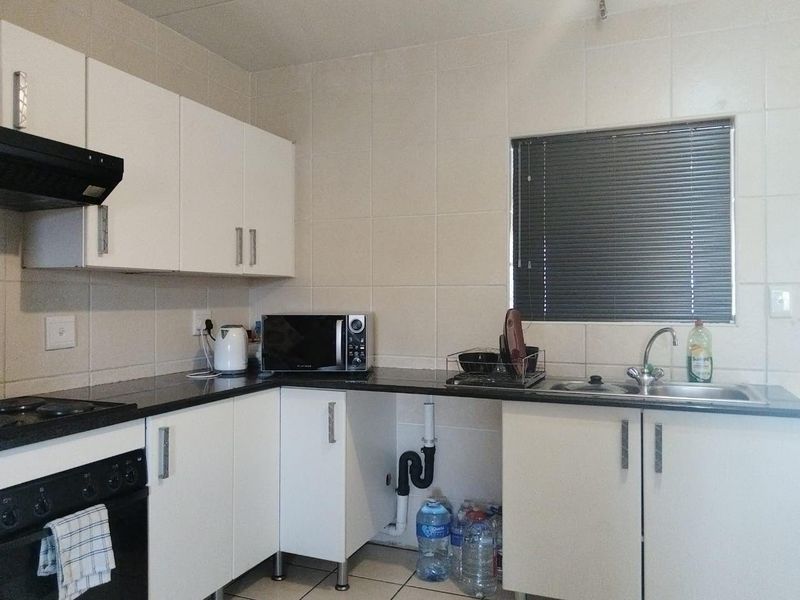 A functional kitchen featuring white cabinetry, dark granite countertops, tiled splashbacks, and an integrated oven with extractor fan. Requires minor repairs to cabinetry.
