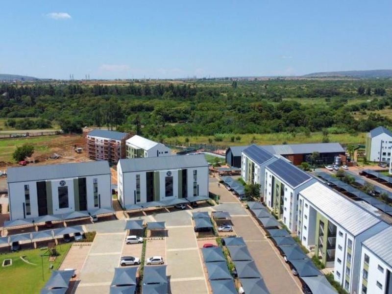 Aerial view of a modern apartment complex featuring multiple residential blocks, extensive covered parking, and landscaped grounds in a suburban setting.