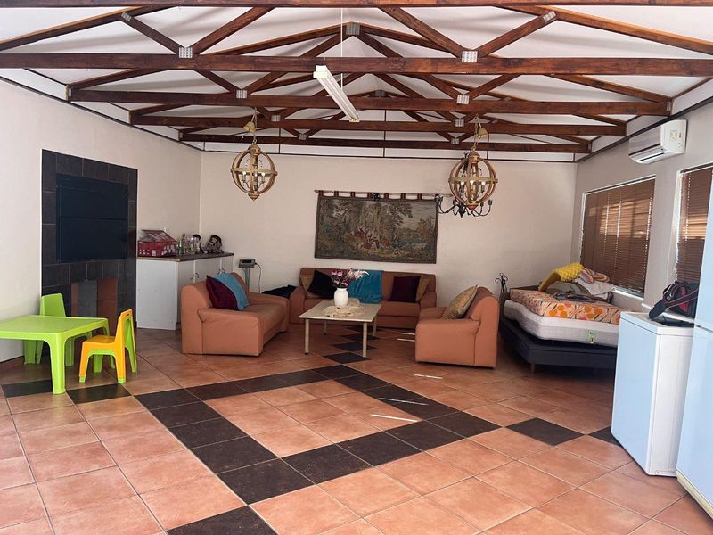 Spacious living area featuring exposed timber roof trusses, tiled flooring, and a built-in fireplace, offering a versatile layout for relaxation and entertainment.