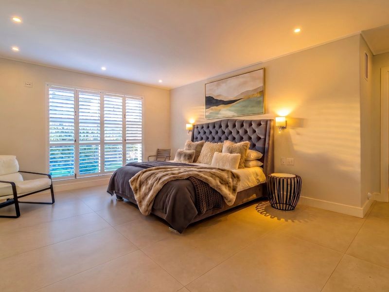 Spacious, well-lit bedroom featuring modern tiled flooring, plantation shutters, and recessed downlighting, creating a comfortable and inviting atmosphere.