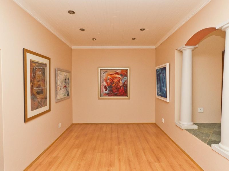 A bright, empty living space featuring laminate flooring, recessed ceiling lighting, and decorative architectural columns framing the entrance.
