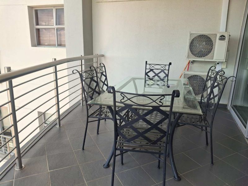 A covered balcony featuring tiled flooring, a stainless steel balustrade, and wall-mounted air conditioning units.