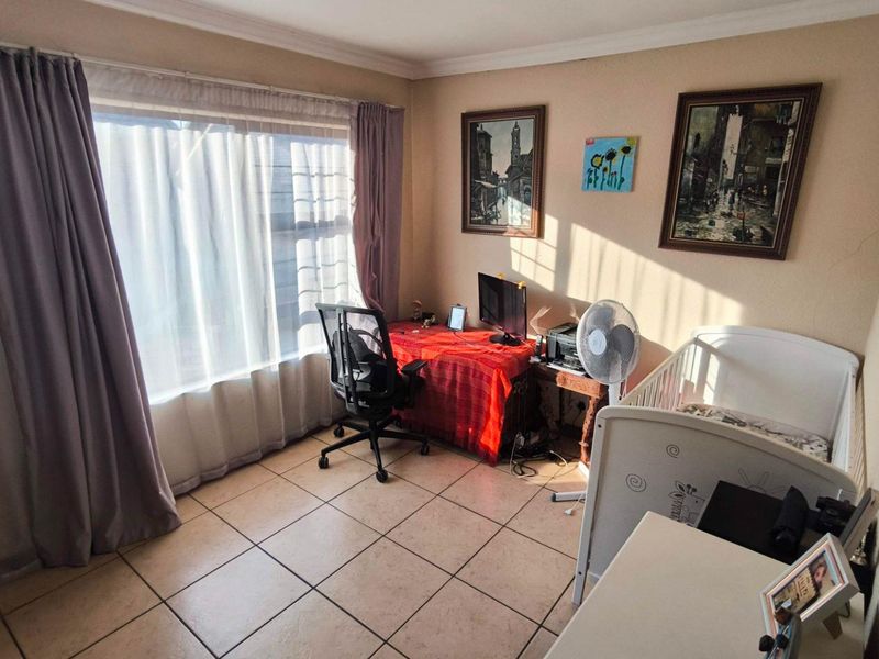 A functional bedroom featuring tiled flooring, cove cornicing, and a large window allowing for natural light.